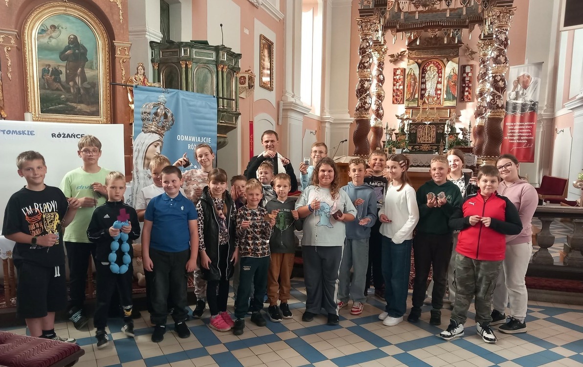 Grupa dzieci wewnątrz kościoła pozuje do zdjęcia wraz z księdzem