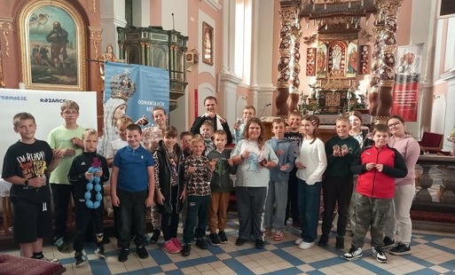 Grupa dzieci wewnątrz kościoła pozuje do zdjęcia wraz z księdzem